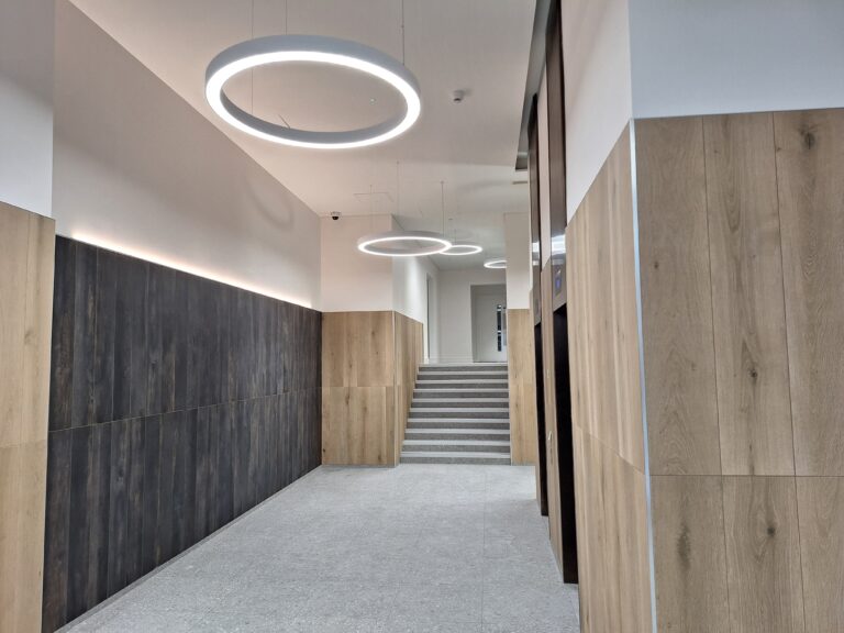 Contemporary lobby at 90 Chancery Lane, illuminated by circular pendant lights and LED wall lighting, highlighting a modern, welcoming design with wood-panelled walls.